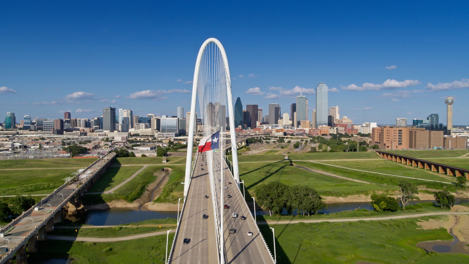 Aerial View of Downtown Dallas with Texas State Flag Flying Over Margaret Hunt Hill Bridge